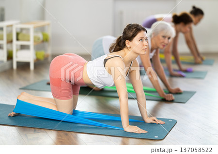 Young girl exercising with resistance band during pilates class Young girl exercising with resistance band during pilates class 137058522