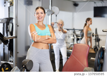 Young girl trainer in sportswear poses in middle of fitness center gym. Young girl trainer in sportswear poses in middle of fitness center gym. 137058595