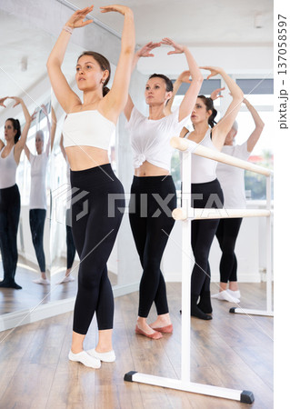 Female ballet dancers doing various ballet movements at ballet barre in fifth position 137058597