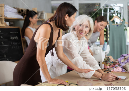 Mature woman drawing on paper during dressmaking classes 137058598
