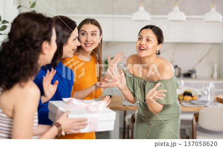Happy Asian woman receiving gift from besties at birthday bash Happy Asian woman receiving gift from besties at birthday bash 137058620