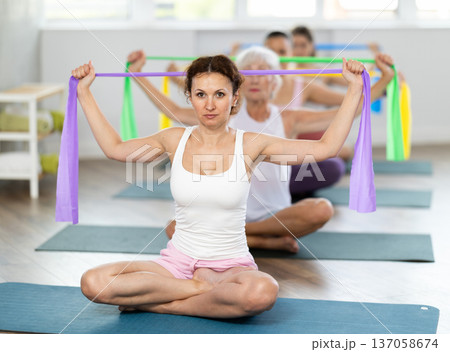 Woman exercising with resistance band in group fitness class Woman exercising with resistance band in group fitness class 137058674