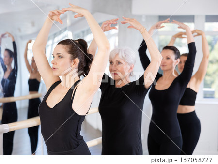 Female ballet dancer executing fifth position during group rehearsal Female ballet dancer executing fifth position during group rehearsal 137058727