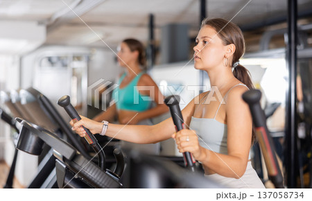 Sporty girl working out on elliptical machine in gym. Healthy active lifestyle concept 137058734