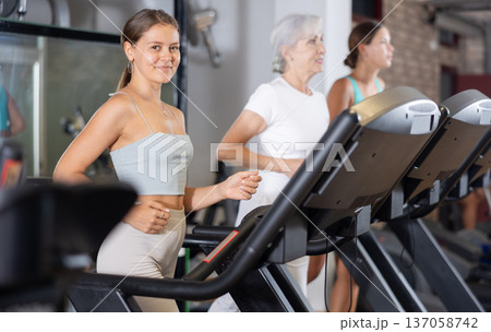 Focused motivated girl leading healthy active lifestyle doing cardio workout in gym, running on treadmill Focused motivated girl leading healthy active lifestyle doing cardio workout in gym, running on treadmill 137058742