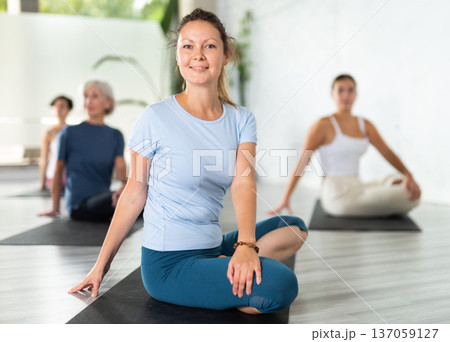 Portrait of women practicing Matsyendrasana known as Lord of Fishes Pose during group yoga training Portrait of women practicing Matsyendrasana known as Lord of Fishes Pose during group yoga training 137059127