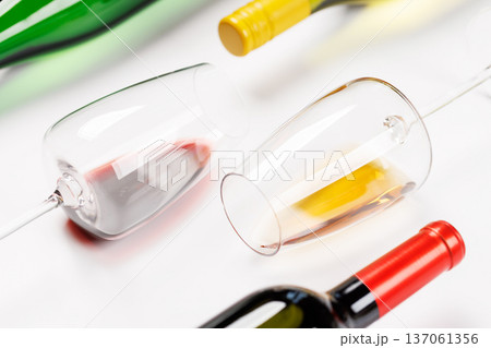 Wine glasses with red and white wine and bottles lying on white background Wine glasses with red and white wine and bottles lying on white background 137061356