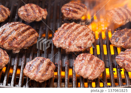 Burger patties grilling with fire and smoke 137061825