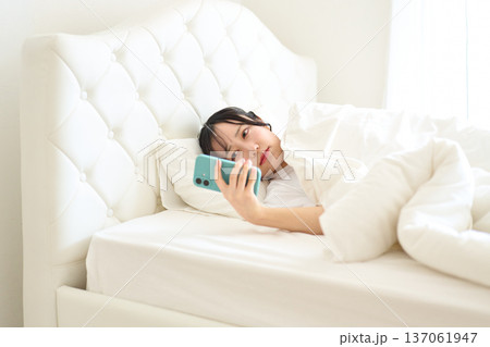 不安な表情でスマートフォンを見る女性 不安な表情でスマートフォンを見る女性 137061947