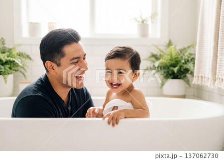 Happy hispanic father washing his toddler son in a white bathtub at home 137062730