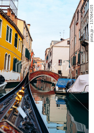View of a canal in Venice with boats and old buildings on a cloudy day 137064105