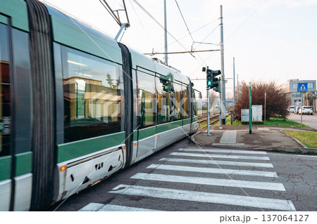 Tram travels through intersection with green signal in urban area during daytime Tram travels through intersection with green signal in urban area during daytime 137064127