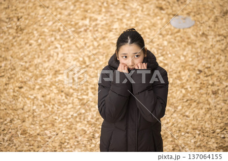 コートを着て寒がる女の子 137064155