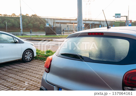 Cars parked near a road with trees and a bridge at sunset in a small town Cars parked near a road with trees and a bridge at sunset in a small town 137064161