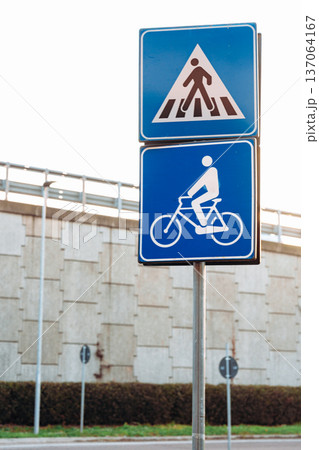 Road signs for pedestrians and cyclists near a wall in an urban area at sunset Road signs for pedestrians and cyclists near a wall in an urban area at sunset 137064167
