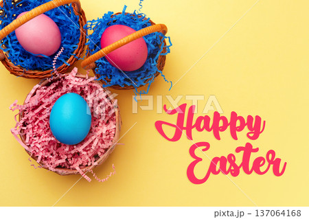 Colorful Easter eggs in baskets with a greeting on a yellow background for celebration Colorful Easter eggs in baskets with a greeting on a yellow background for celebration 137064168