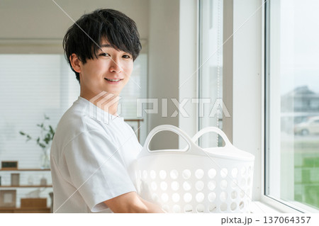 洗濯かごを持つTシャツ姿の若いアジア人男性 洗濯かごを持つTシャツ姿の若いアジア人男性 137064357