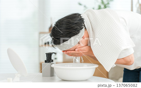 ヘアバンドをして洗顔をする若いアジア人男性 137065082
