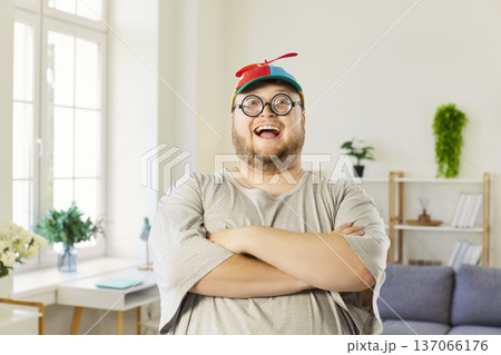 Cheerful plus-size man in propeller beanie and nerd glasses with arms crossed Cheerful plus-size man in propeller beanie and nerd glasses with arms crossed 137066176