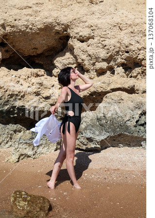 A woman in a black bathing suit went into the sea at a resort town beach to dance and take photos A woman in a black bathing suit went into the sea at a resort town beach to dance and take photos 137068104