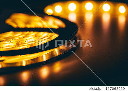 Coiled warm LED strip light with glowing bokeh background, modern smart home lighting concept Coiled warm LED strip light with glowing bokeh background, modern smart home lighting concept 137068920