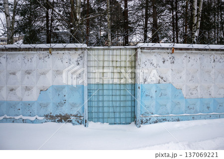 Winter scene with a weathered concrete fence topped with barbed wire and block gate 137069221