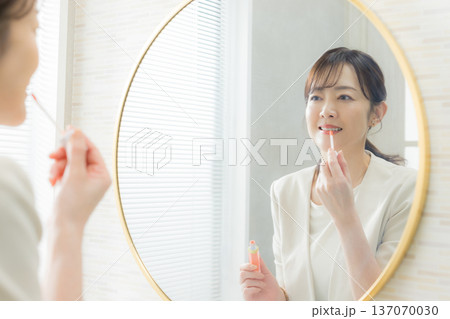 鏡を見てメイクする女性 137070030