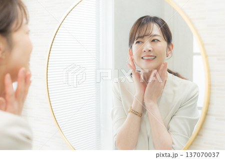 鏡を見てメイクする女性 137070037