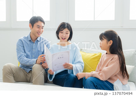 リビングで通知表を見る家族　 137070494