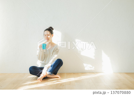 床に座ってコーヒーを飲む若い女性 床に座ってコーヒーを飲む若い女性 137070880