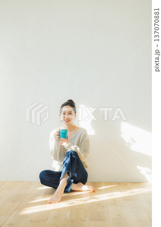 床に座ってコーヒーを飲む若い女性　 137070881