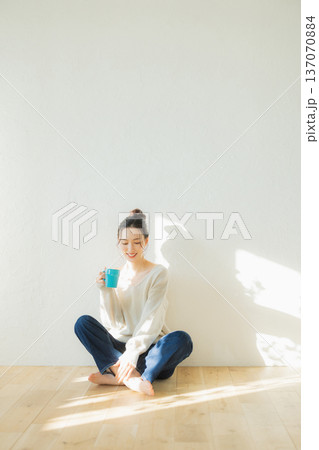 床に座ってコーヒーを飲む若い女性 床に座ってコーヒーを飲む若い女性 137070884