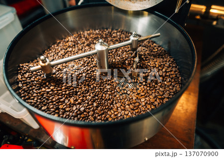 reshly roasted coffee beans mixing in a commercial coffee roaster machine. reshly roasted coffee beans mixing in a commercial coffee roaster machine. 137070900