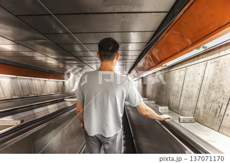Man descending on escalator in subway tunnel during daily urban commute 137071170