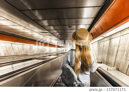 Young woman descending escalator in metro tunnel, urban travel and public transportation concept Young woman descending escalator in metro tunnel, urban travel and public transportation concept 137071171