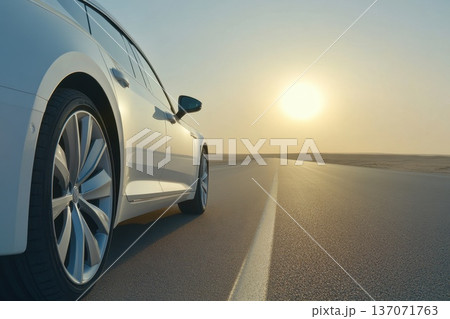 Low Angle Shot of a Car Wheel on an Open Highway with a Beautiful Sunset View 137071763