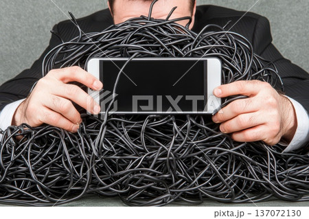 Person Holding Smartphone Surrounded by Tangle of Wires and Cables Like Lifeline Person Holding Smartphone Surrounded by Tangle of Wires and Cables Like Lifeline 137072130