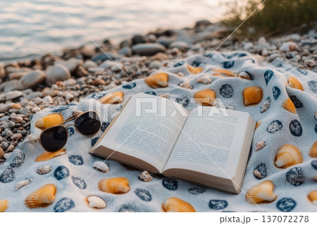 Peaceful Morning by the Shore with Beach Blanket, Book, and Sunglasses on the Sand 137072278
