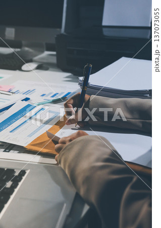 business documents on office table with tablet, smart phone and laptop and two colleagues discussing data business documents on office table with tablet, smart phone and laptop and two colleagues discussing data 137073055
