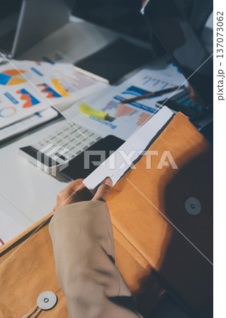 business documents on office table with tablet, smart phone and laptop and two colleagues discussing data business documents on office table with tablet, smart phone and laptop and two colleagues discussing data 137073062