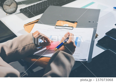 business documents on office table with tablet, smart phone and laptop and two colleagues discussing data business documents on office table with tablet, smart phone and laptop and two colleagues discussing data 137073068