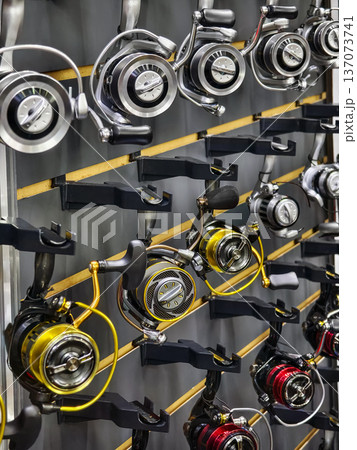 Fishing reels on display in a shop showing various brands during a busy shopping day 137073741
