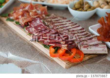 Gourmet charcuterie board with sliced meats, olives, and peppers on wooden tray for appetizer spread Gourmet charcuterie board with sliced meats, olives, and peppers on wooden tray for appetizer spread 137073867