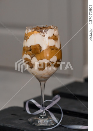 Elegant Dessert Parfait in Wine Glass with Cream Layers, Chocolate Crumbs, and Golden Custard Topping Elegant Dessert Parfait in Wine Glass with Cream Layers, Chocolate Crumbs, and Golden Custard Topping 137073905