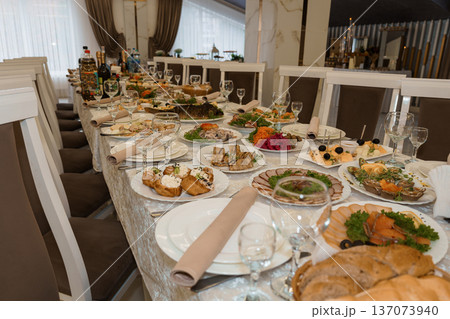 Elegant Long Banquet Table Set for Luxury Dining with Fine China, Crystal Glassware, and Gourmet?? in a Refined Restaurant Setting Elegant Long Banquet Table Set for Luxury Dining with Fine China, Crystal Glassware, and Gourmet?? in a Refined Restaurant Setting 137073940