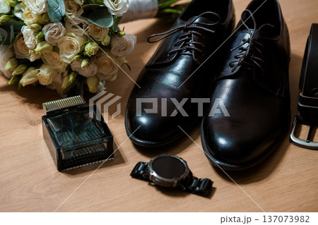 Elegant Black Dress Shoes Beside Wedding Bouquet and Accessories on Wooden Surface 137073982