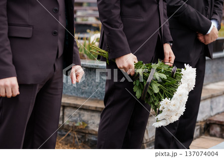 Men in Dark Suits Holding White Chrysanthemums at a Funeral Ceremony in a Cemetery Men in Dark Suits Holding White Chrysanthemums at a Funeral Ceremony in a Cemetery 137074004