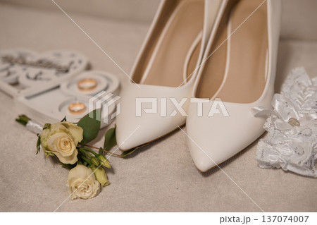 Elegant White Wedding Shoes with Rose Bouquet and Ring Box on Soft Beige Background Elegant White Wedding Shoes with Rose Bouquet and Ring Box on Soft Beige Background 137074007