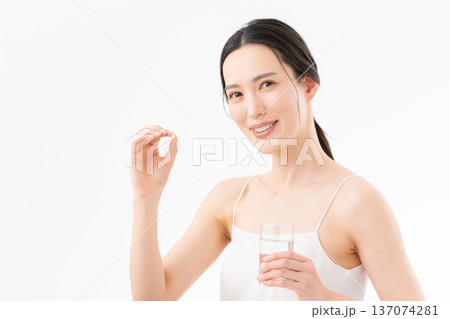 白背景でサプリを飲む女性の健康イメージ 白背景でサプリを飲む女性の健康イメージ 137074281