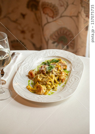 Pasta with shrimp in creamy pesto sauce 137075735